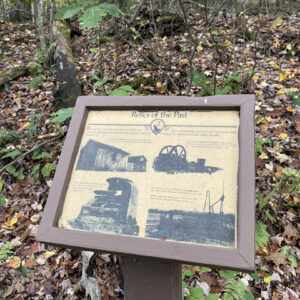 Placard along hiking trail with examples of oil equipment used in the area